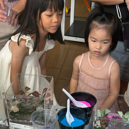 Kids crafting terrariums with colorful sand and plants in Singapore workshops
